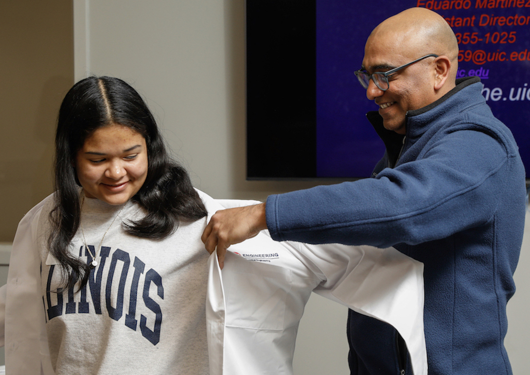 University of Illinois Chicago College of Engineering's Vikas Berry presents a lab coat to a potential ChE undergraduate student as part of a recruitment event.