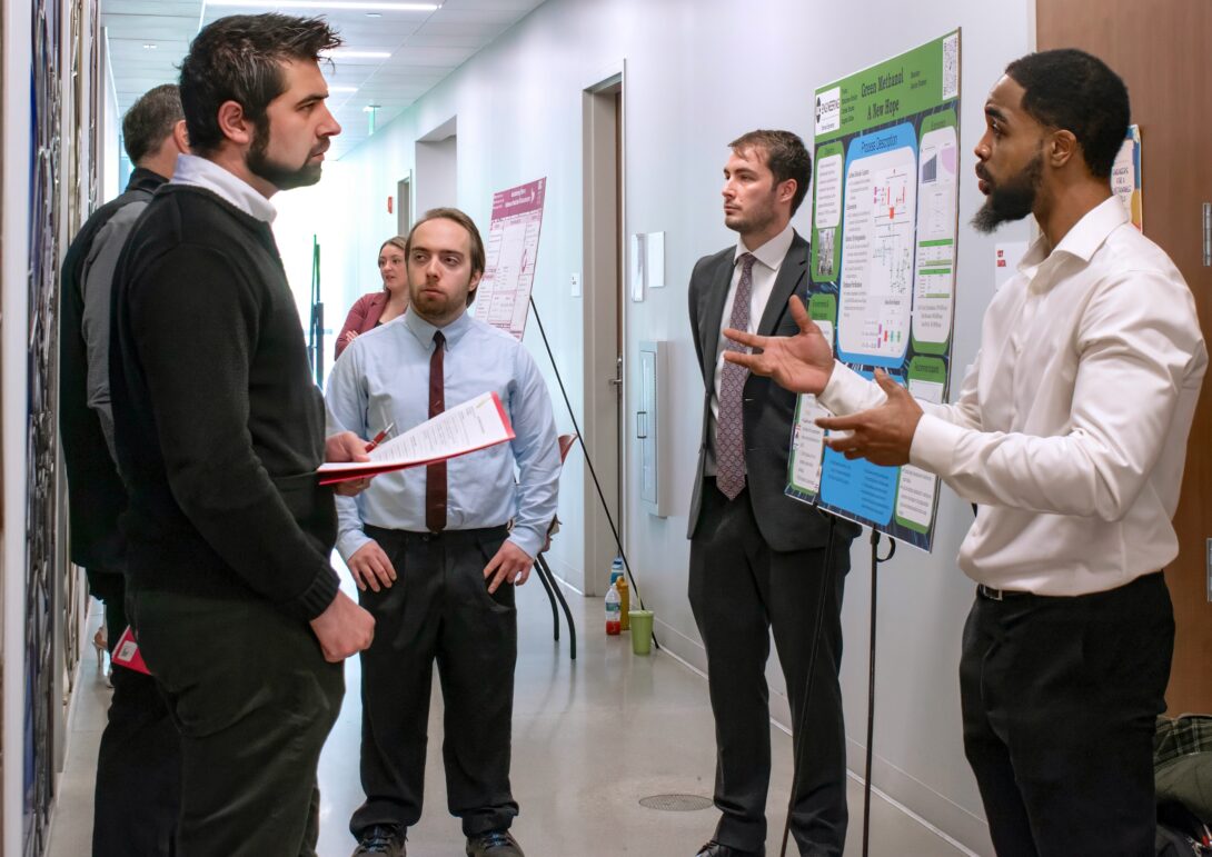 Senior Angelo Giles (right) tells visitors about his senior design project that focused on creating green methanol